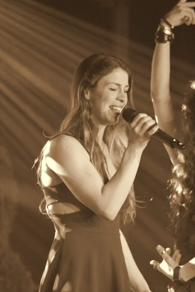 Animation d'événements avec Emilie, gérante de Crazy 2 Night chante au micro. Photo avec filtre sepia.