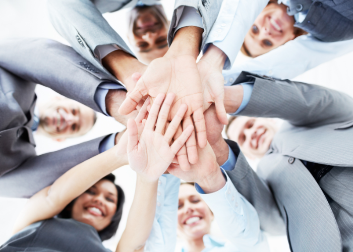 Séminaire. Photo de salariés en cercle posant leurs mains les unes sur les autres formant une étoile.